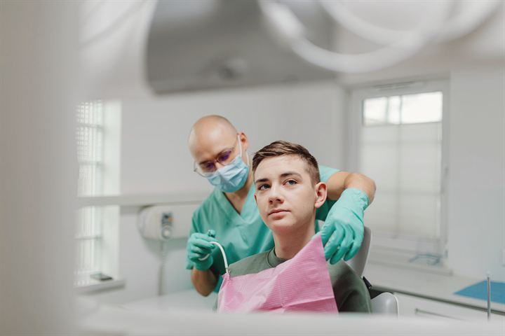 Dentista atendiendo a un adolescente en el sillón